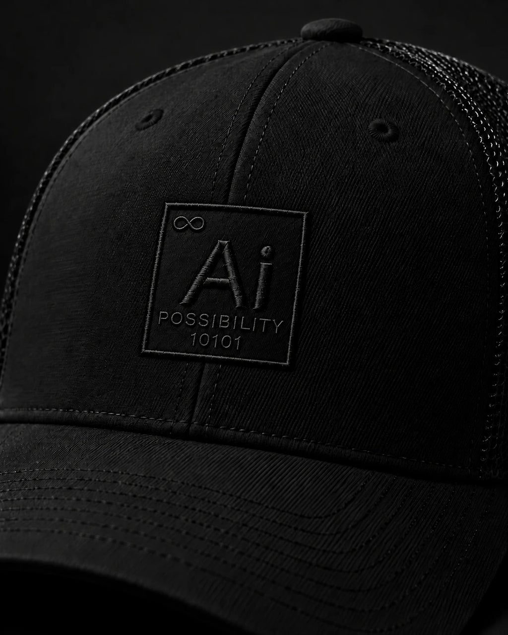 Close-up of the tone-on-tone embroidered Ai + You element tile on the front panel of the Possibility Trucker Hat